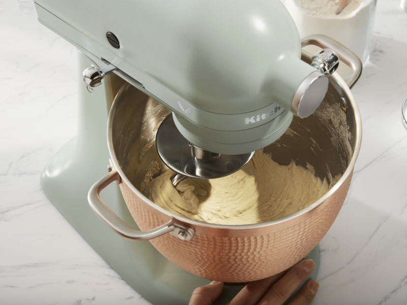 Person making pretzel dough in rose gold, textured stand mixer bowl Person making pretzel dough in rose gold, textured stand mixer bowl