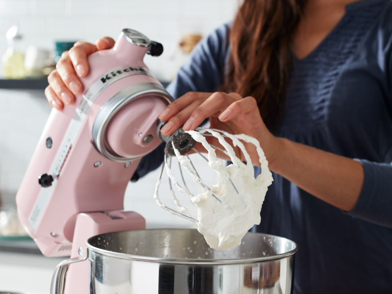 A woman using a pink KitchenAid® stand mixer to make homemade whipped cream A woman using a pink KitchenAid® stand mixer to make homemade whipped cream