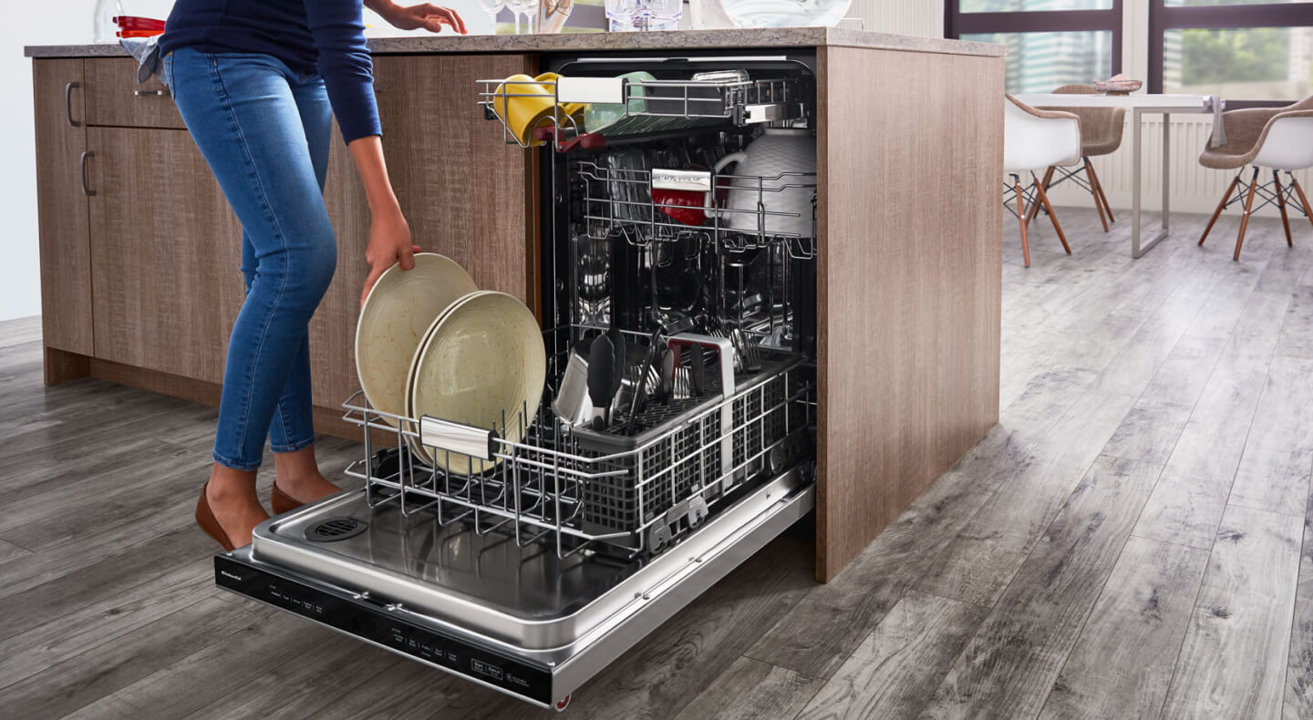 A woman placing a plate in a dishwasher A woman placing a plate in a dishwasher