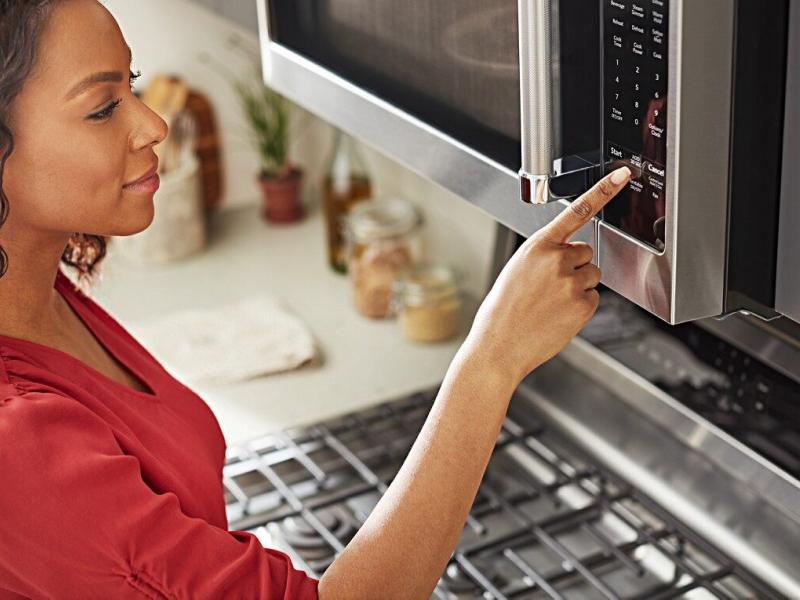 A Finger pressing a button on a microwave