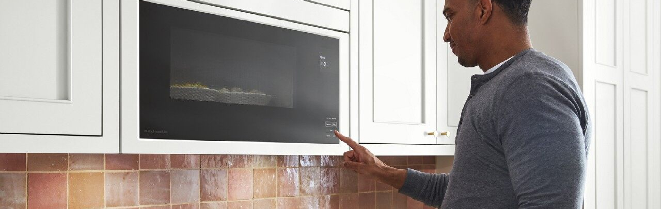 A Finger pressing a start button on a microwave