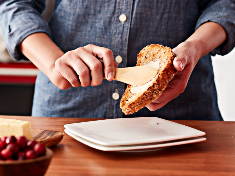Person buttering a slice of bread Person buttering a slice of bread