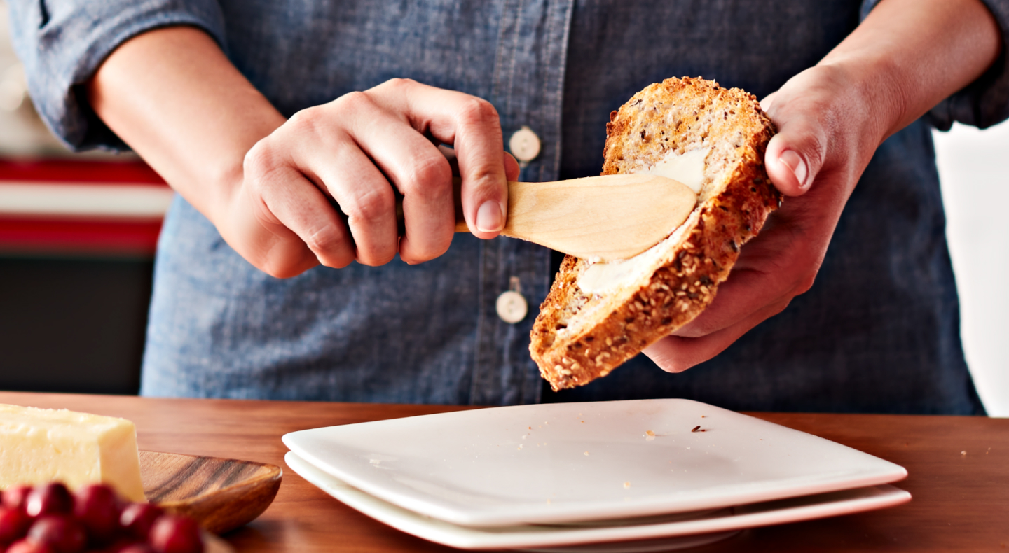 Person buttering a slice of bread Person buttering a slice of bread