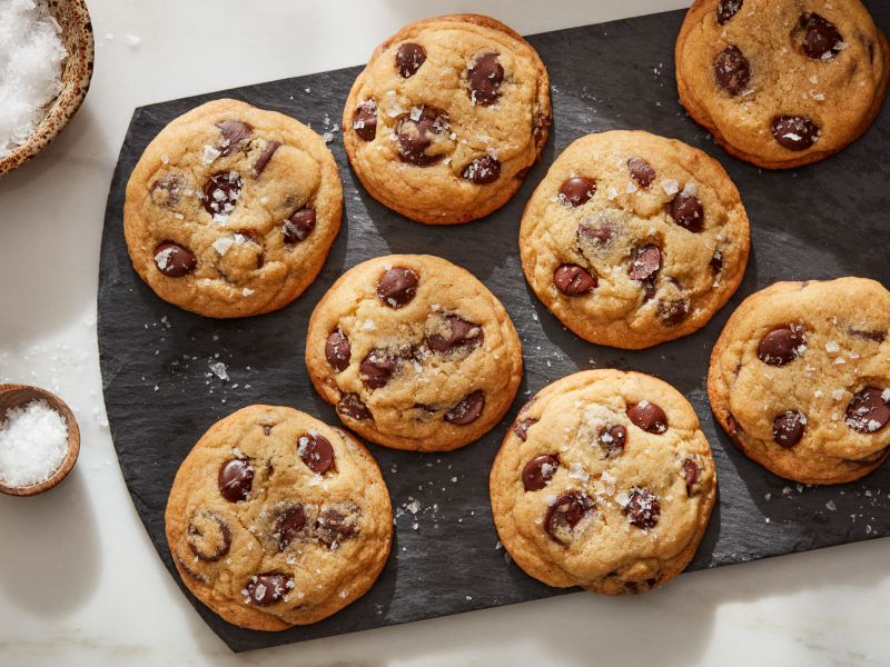 Sea salt miso chocolate chunk cookies on a board next to bowl of sea salt Sea salt miso chocolate chunk cookies on a board next to bowl of sea salt