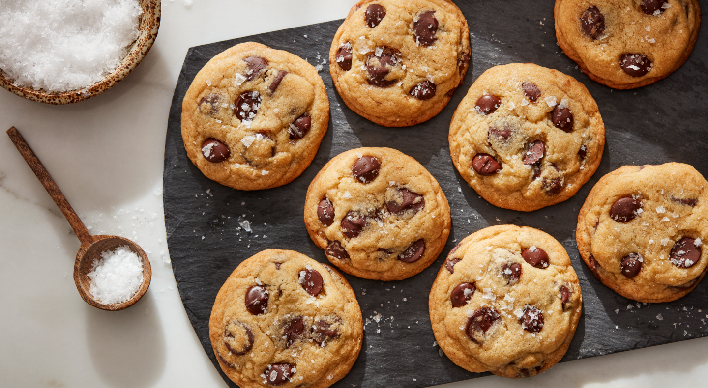 Sea salt miso chocolate chunk cookies on a board next to bowl of sea salt Sea salt miso chocolate chunk cookies on a board next to bowl of sea salt
