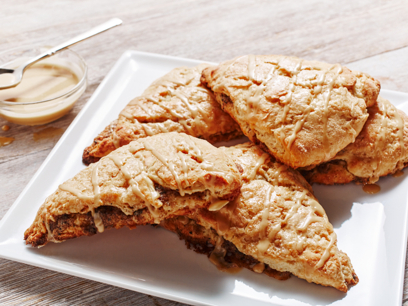 Cinnamon coffee scones on a plate next to honey butter serving dish Cinnamon coffee scones on a plate next to honey butter serving dish