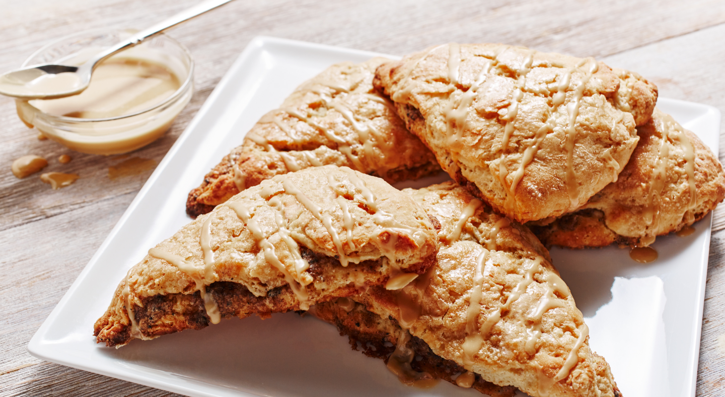 Cinnamon coffee scones on a plate next to honey butter serving dish Cinnamon coffee scones on a plate next to honey butter serving dish