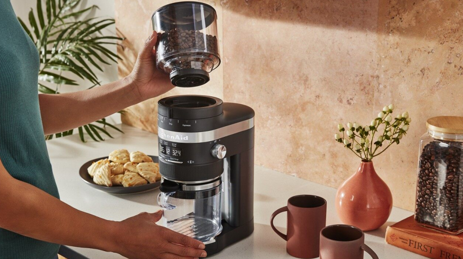 Coffee beans being placed on the base of burr coffee grinder. Coffee beans being placed on the base of burr coffee grinder.