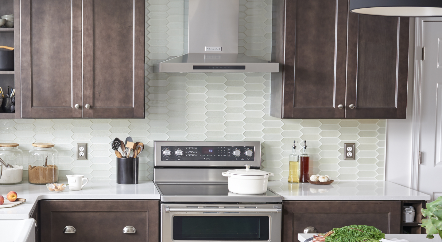 Wall-mount canopy hood between brown cabinets Wall-mount canopy hood between brown cabinets