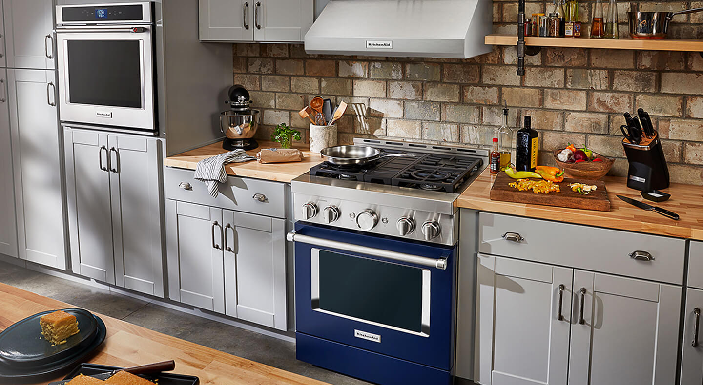 A peninsula kitchen with a wall oven and commercial-style, ink blue range