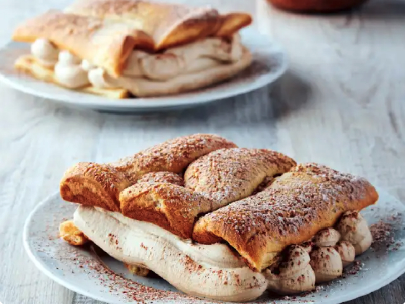 A plated eclair cake with sprinkled cocoa powder