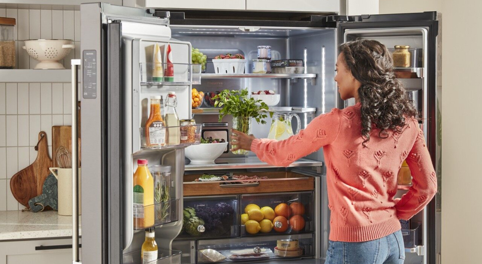 Woman in pink sweater putting herbs in French door type of refrigerator