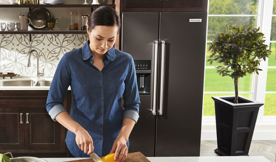 Woman preparing food in front of side-by-side fridge type in modern kitchen
