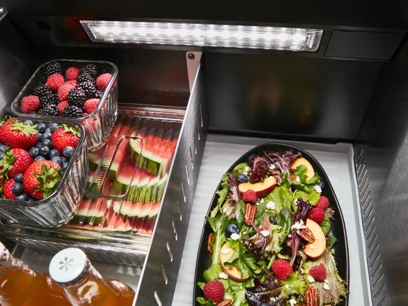 Fresh fruit and a salad stored inside a refrigerator Fresh fruit and a salad stored inside a refrigerator