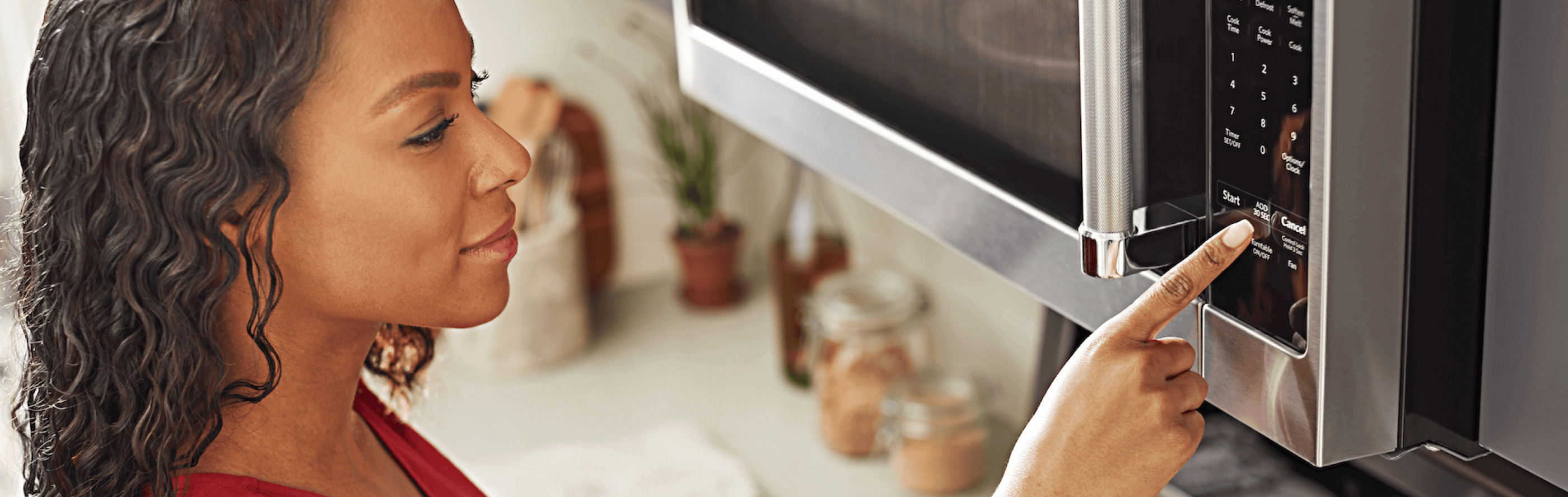 A person selecting a microwave setting on an over-the-range KitchenAid® microwave.