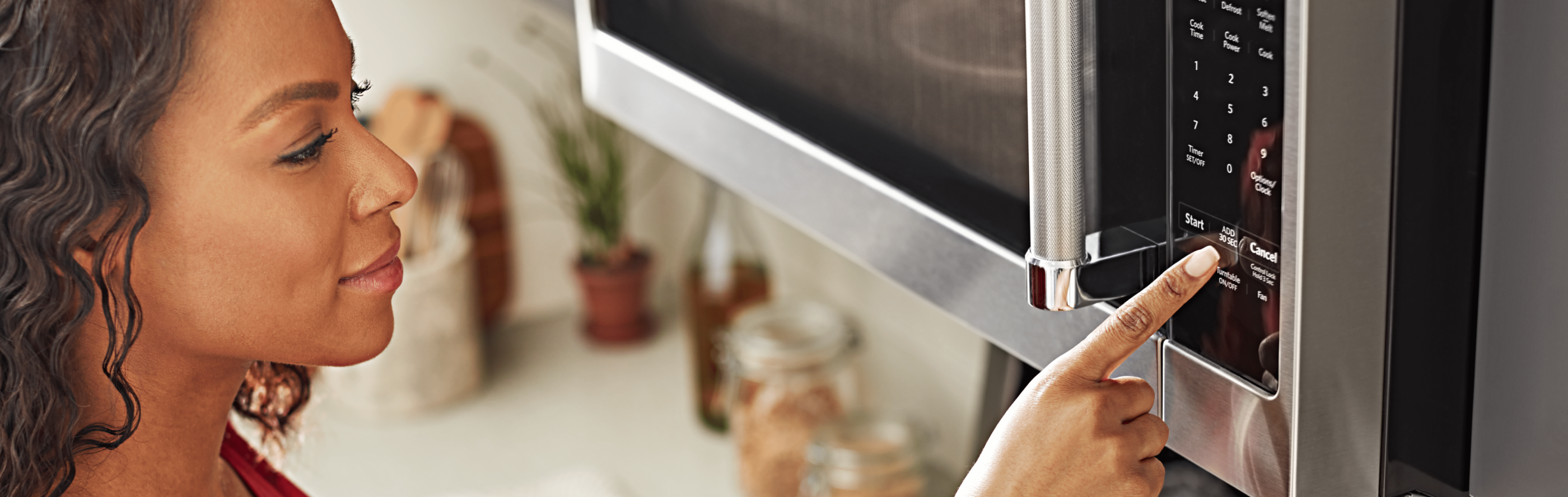A person selecting a microwave setting on an over-the-range KitchenAid® microwave.