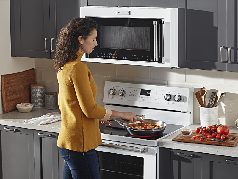 Person adding ingredients to a skillet on an electric stovetop  Person adding ingredients to a skillet on an electric stovetop