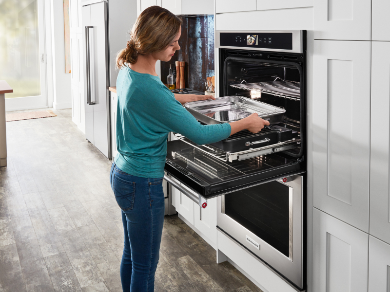 Woman removing baking sheet from the oven Woman removing baking sheet from the oven