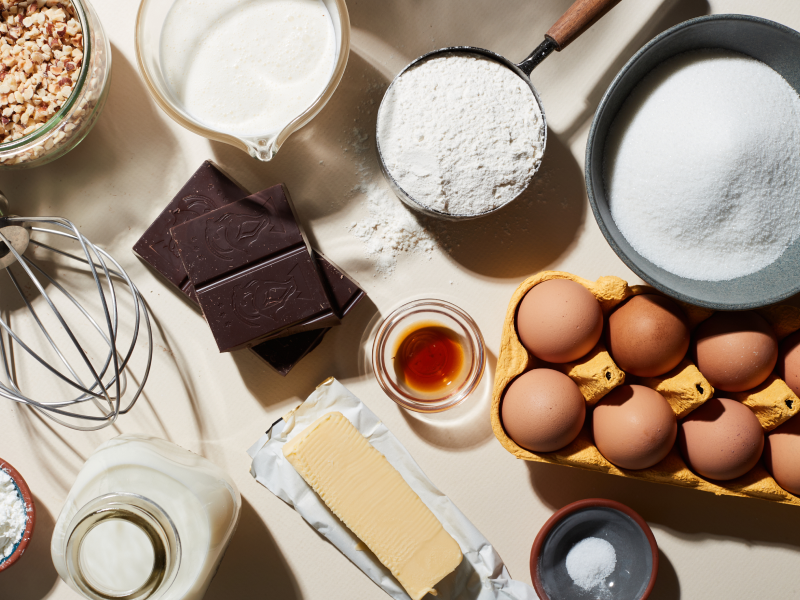 Top view of whisk attachment and pie ingredients including flour, sugar, eggs, butter, milk, chocolate and walnuts Top view of whisk attachment and pie ingredients including flour, sugar, eggs, butter, milk, chocolate and walnuts