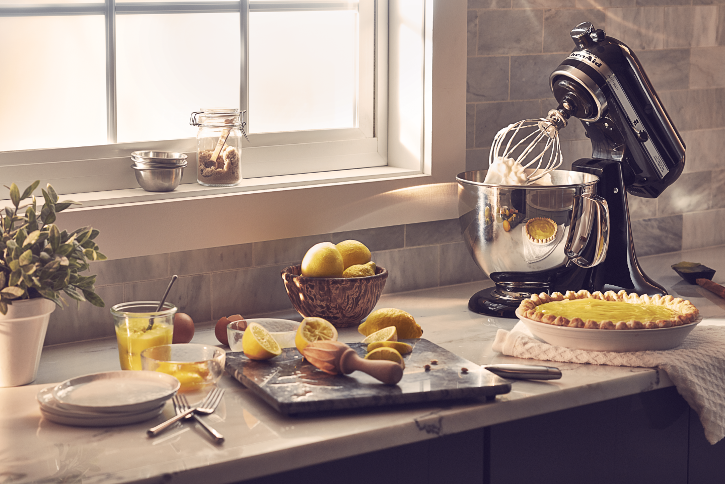 Black KitchenAid® stand mixer on countertop next to lemon custard pie with other baking ingredients Black KitchenAid® stand mixer on countertop next to lemon custard pie with other baking ingredients