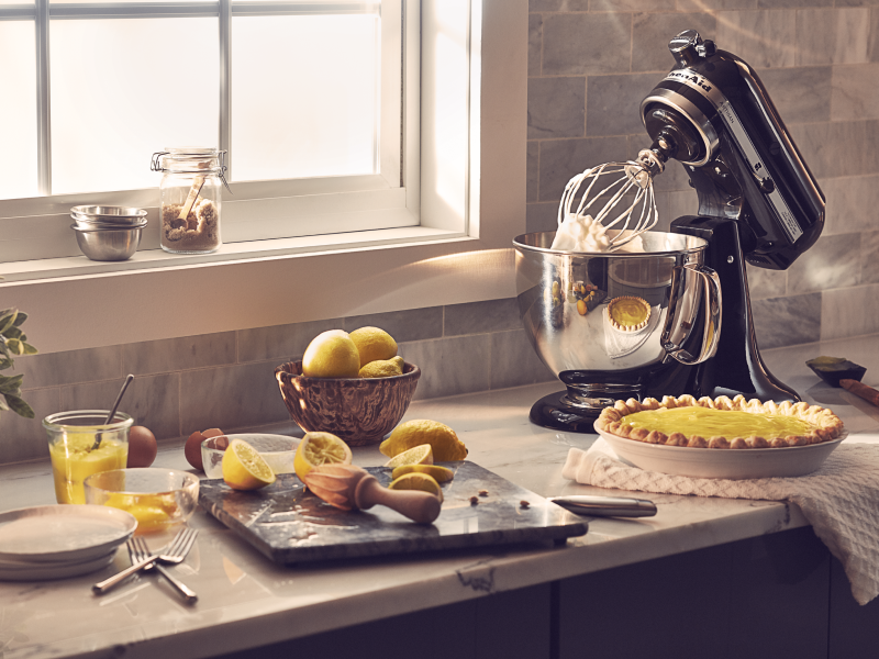 Black KitchenAid® stand mixer on countertop next to lemon custard pie with other baking ingredients Black KitchenAid® stand mixer on countertop next to lemon custard pie with other baking ingredients