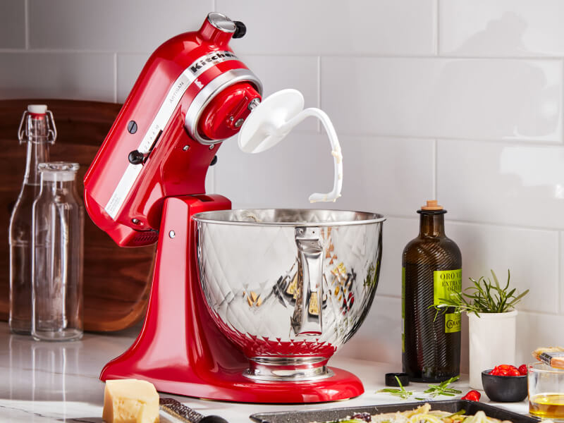 A KitchenAid® stand mixer with a dough hook accessory on the counter of a modern kitchen.