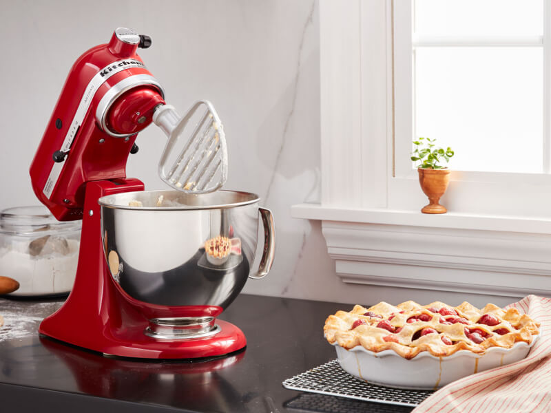 A KitchenAid® stand mixer with a pastry beater accessory next to a pie on the counter of a modern kitchen. A KitchenAid® stand mixer with a pastry beater accessory next to a pie on the counter of a modern kitchen.
