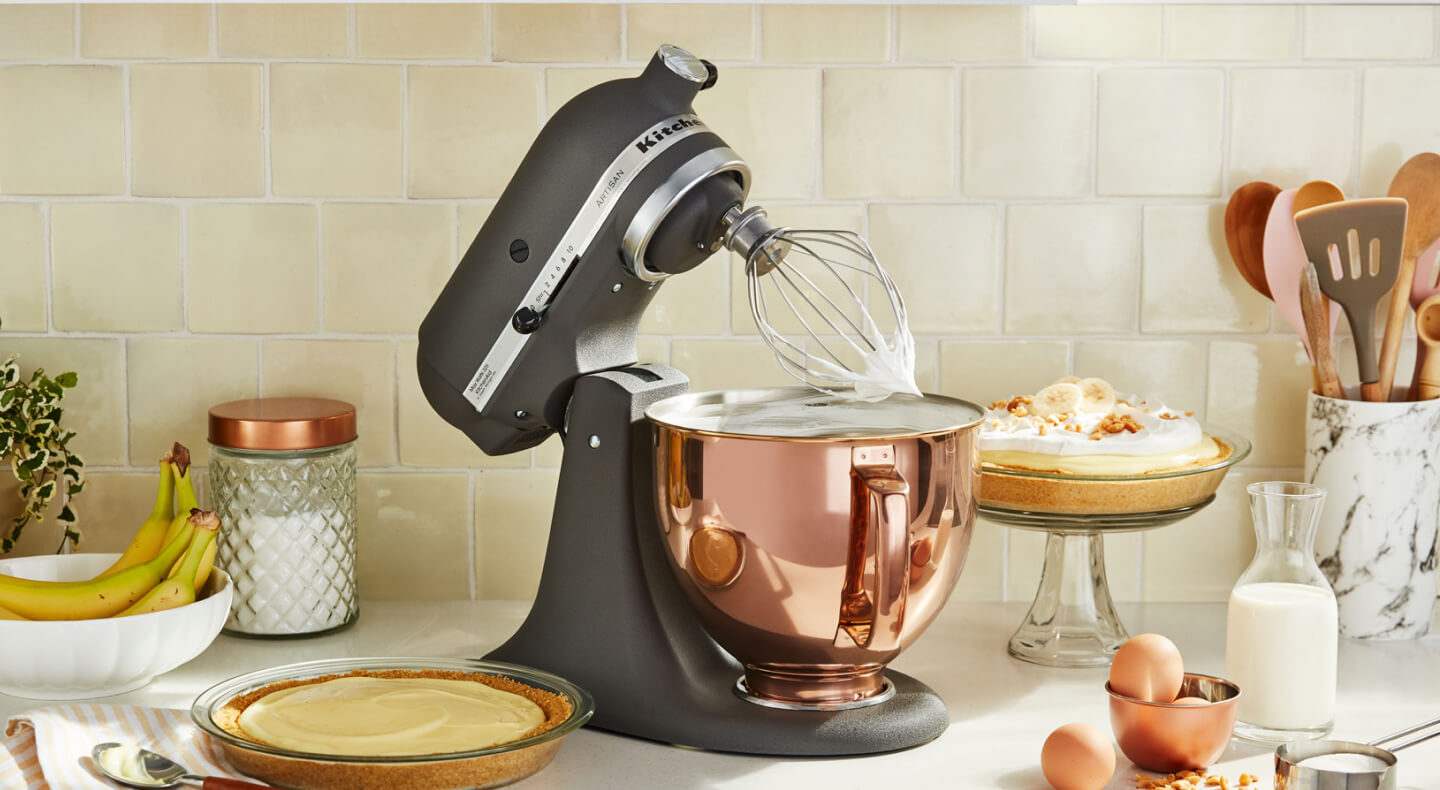 A KitchenAid® stand mixer with a wire whisk/whip accessory with fresh whipped egg whites on the counter of a modern kitchen. A KitchenAid® stand mixer with a wire whisk/whip accessory with fresh whipped egg whites on the counter of a modern kitchen.