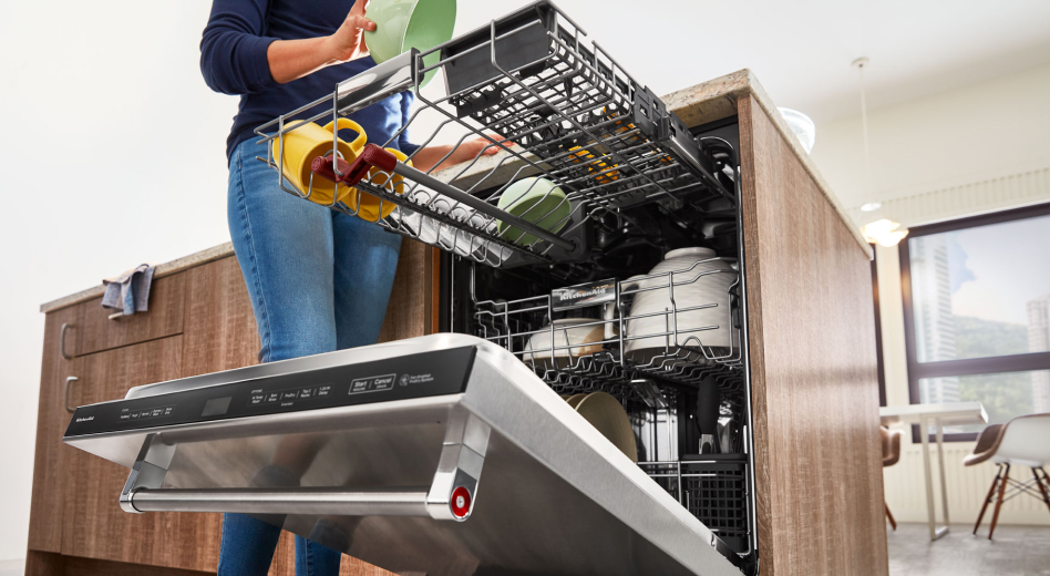 Person loading the top third rack of a dishwasher with a green bowl  Person loading the top third rack of a dishwasher with a green bowl