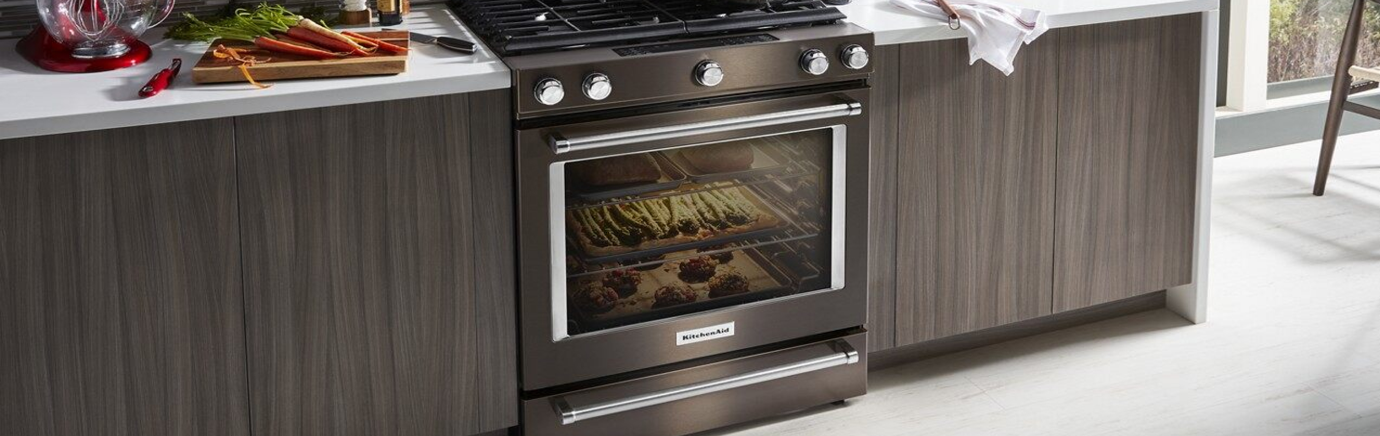 Black stainless steel KitchenAid® range next to dark cabinets