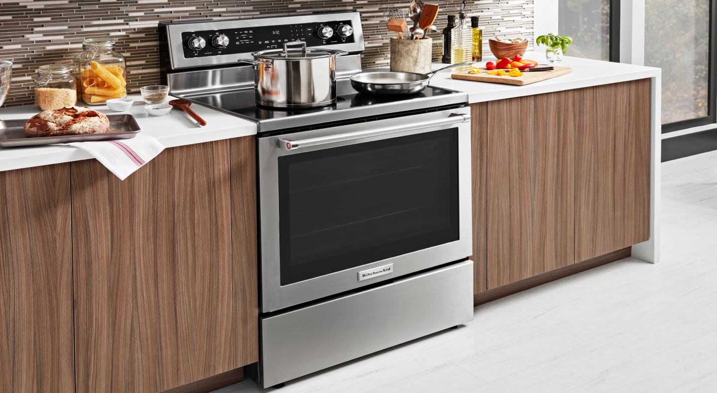 An electric range in a kitchen with pots and pans on top