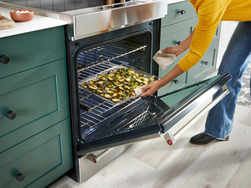 A person pulling air-fried vegetables and potatoes out of a Air Fry Range