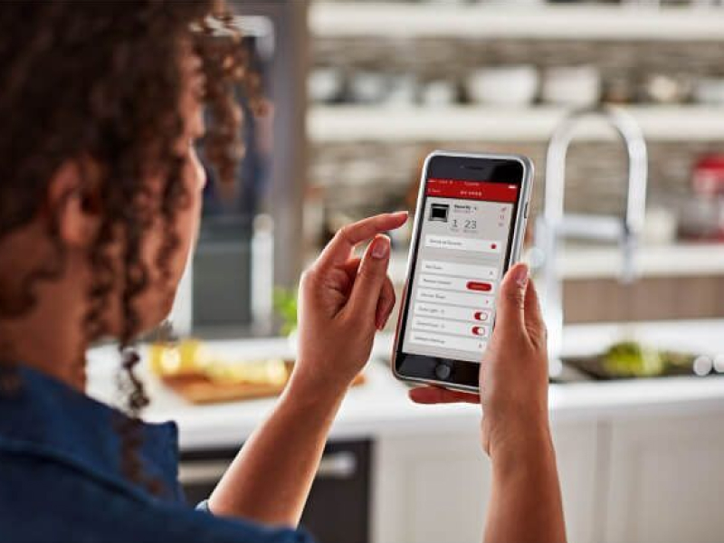 A woman using the KitchenAid® smart appliance app on a mobile device