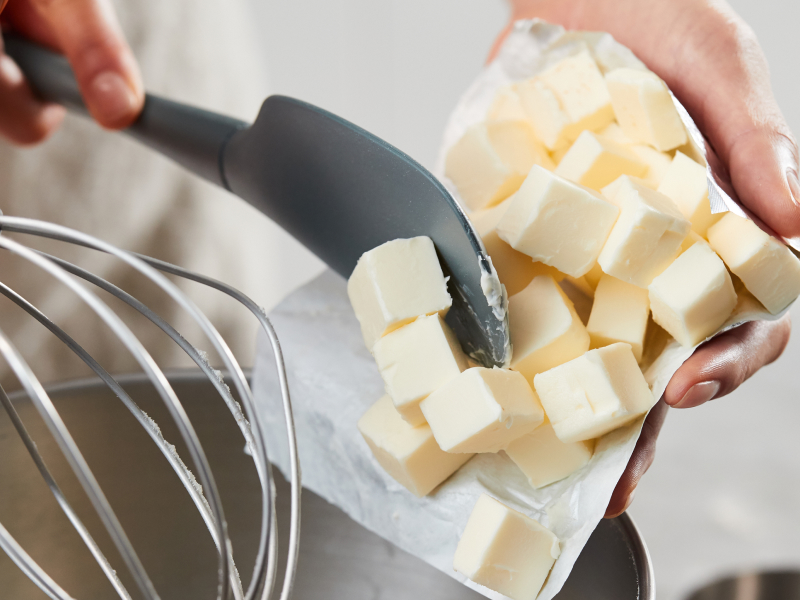A person putting cubed shortening into a stand mixer bowl A person putting cubed shortening into a stand mixer bowl