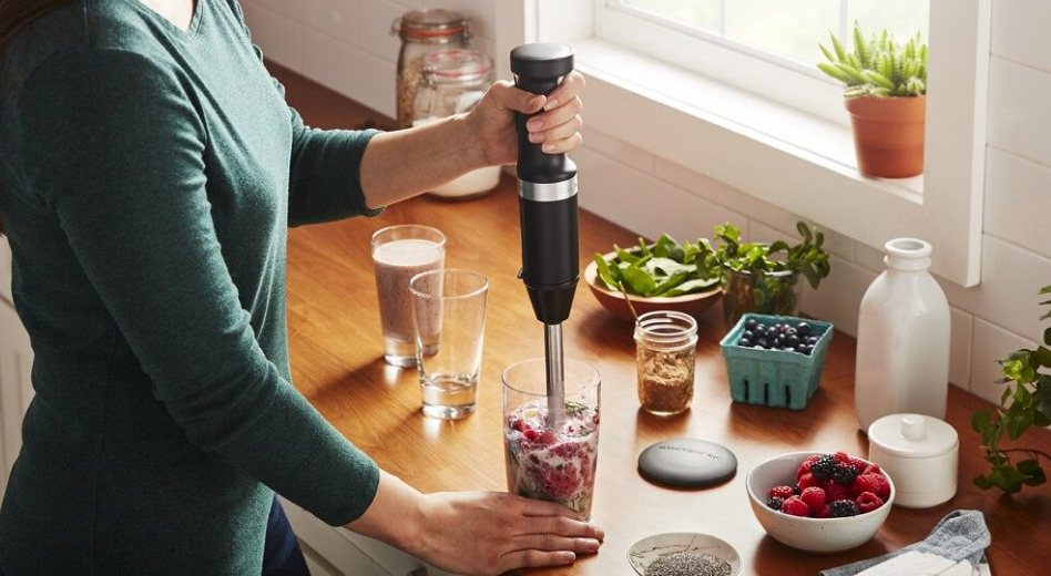 Woman blending smoothie with black KitchenAid® cordless immersion blender Woman blending smoothie with black KitchenAid® cordless immersion blender
