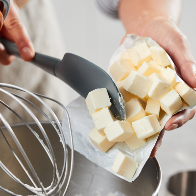Person putting butter into a mixer bowl