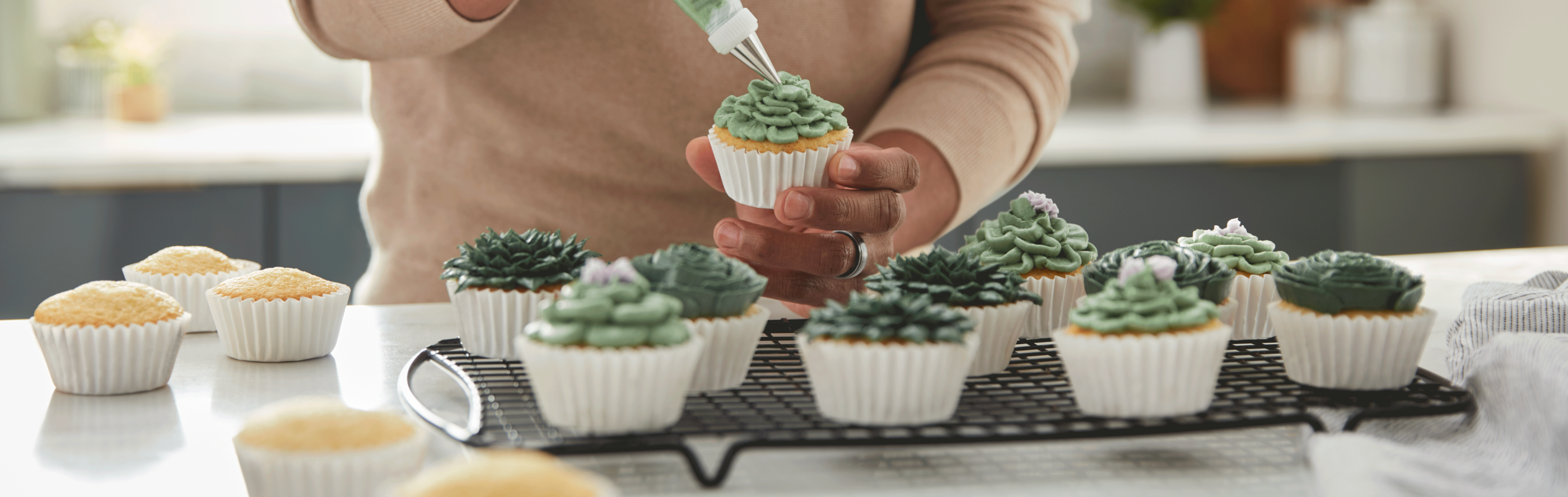 Person piping frosting onto a cupcake
