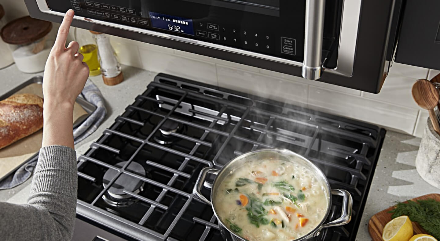 Person selecting a setting on a microwave hood combination Person selecting a setting on a microwave hood combination