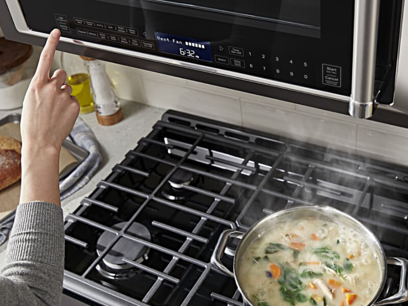 Person selecting a setting on a microwave hood combination Person selecting a setting on a microwave hood combination