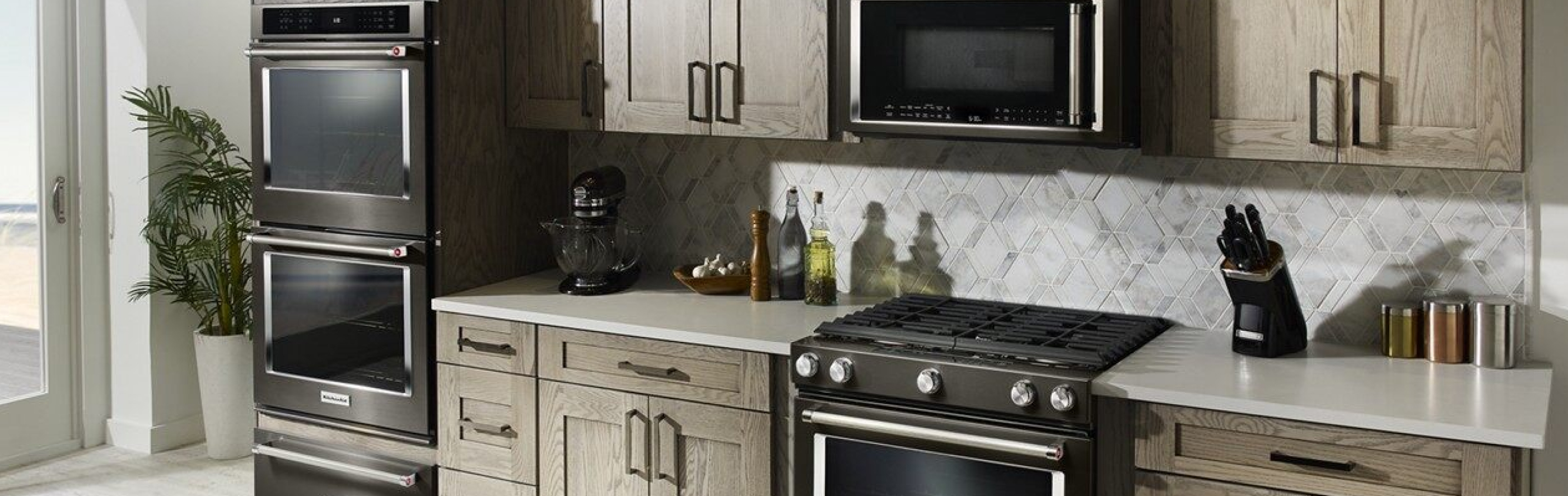 A black range, wall oven, microwave and warming drawer in a kitchen.