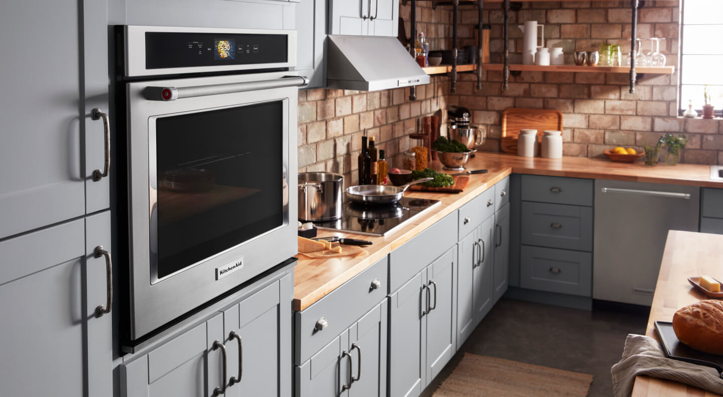 A KitchenAid® wall oven and other appliances in a kitchen with blue cabinets A KitchenAid® wall oven and other appliances in a kitchen with blue cabinets