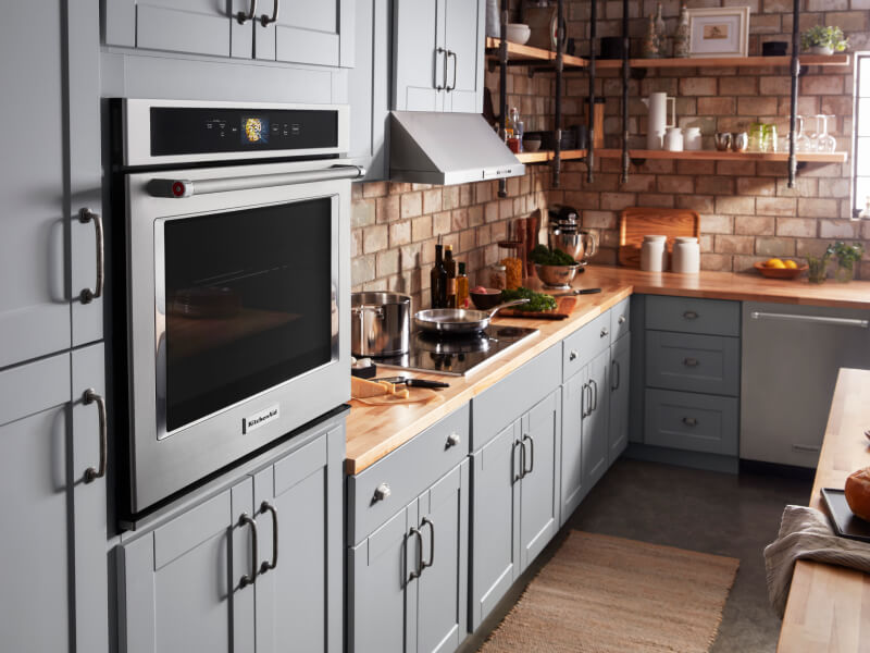 A KitchenAid® wall oven and other appliances in a kitchen with blue cabinets A KitchenAid® wall oven and other appliances in a kitchen with blue cabinets