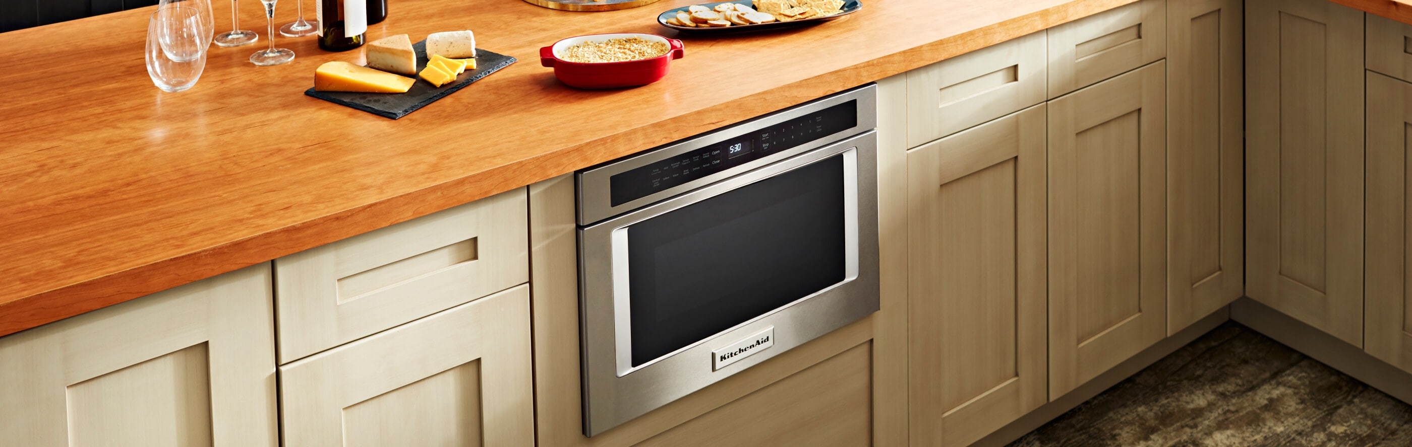 A KitchenAid® microwave drawer below a counter with various food items