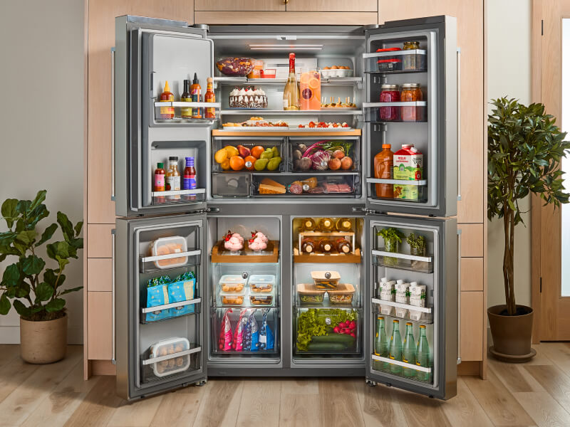A KitchenAid® four door refrigerator with all compartments fully stocked and opened