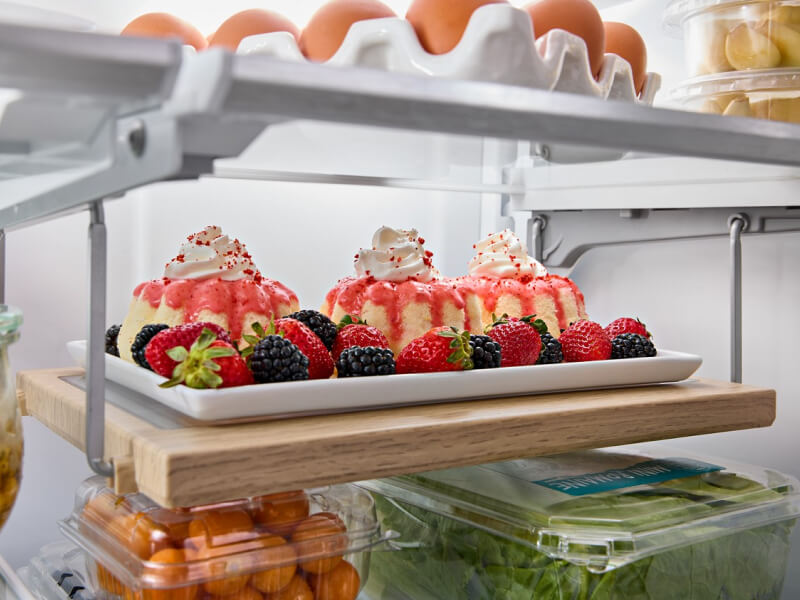 Three small bundt cakes with berries inside a KitchenAid® refrigerator