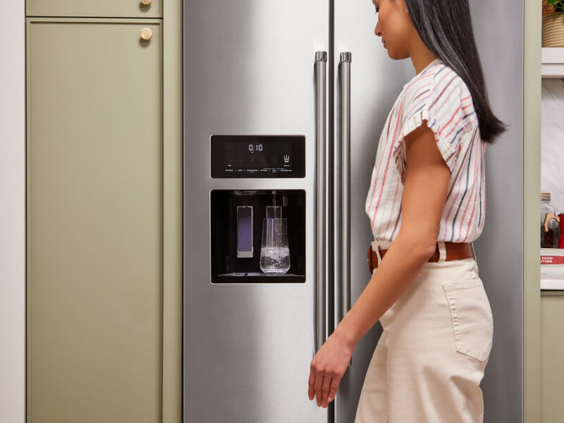 Person filling a water pitcher at the refrigerator
