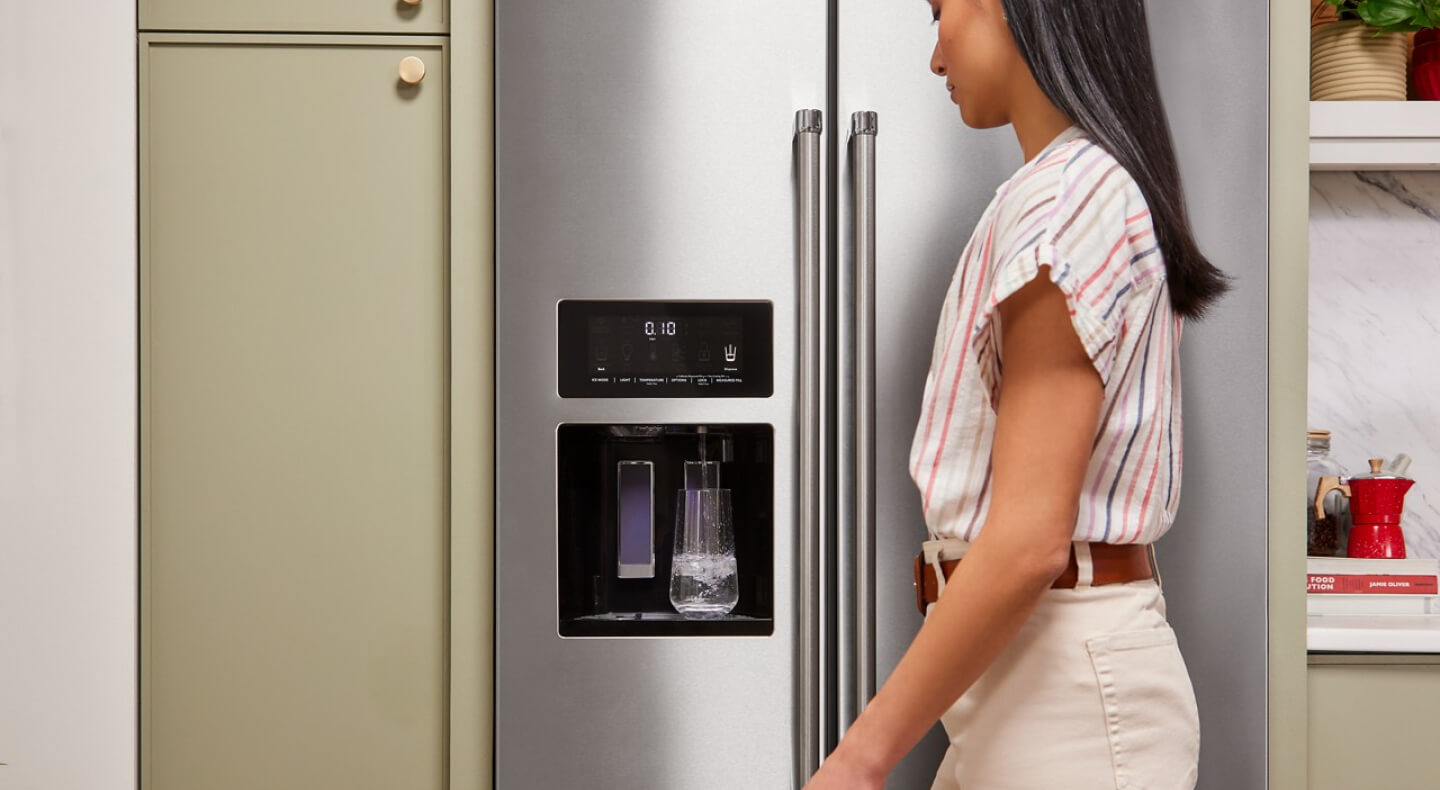 Person filling a water pitcher at the refrigerator