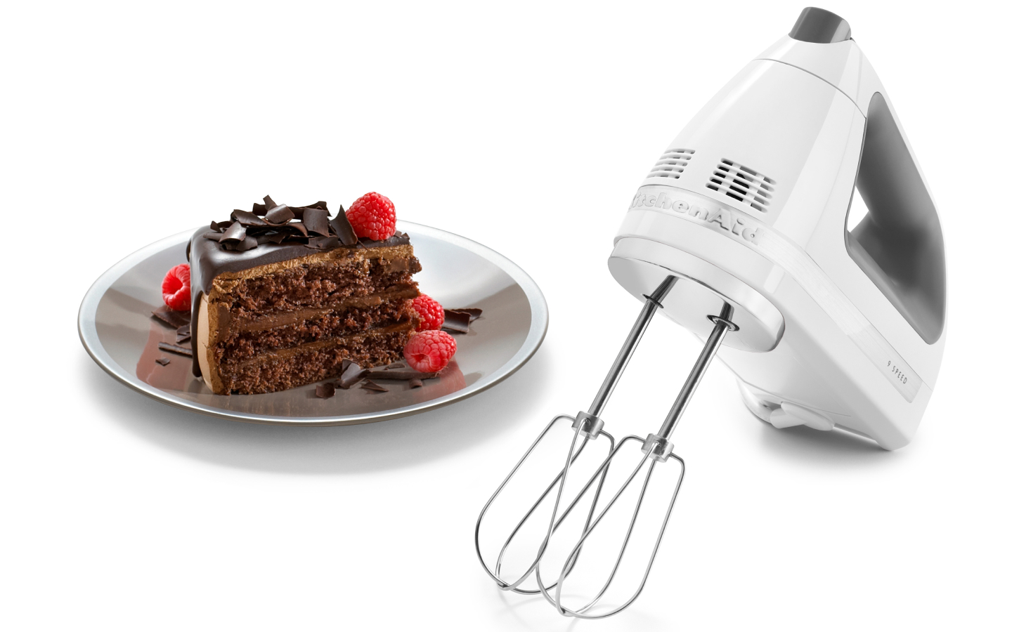 KitchenAid® hand mixer next to slice of chocolate cake