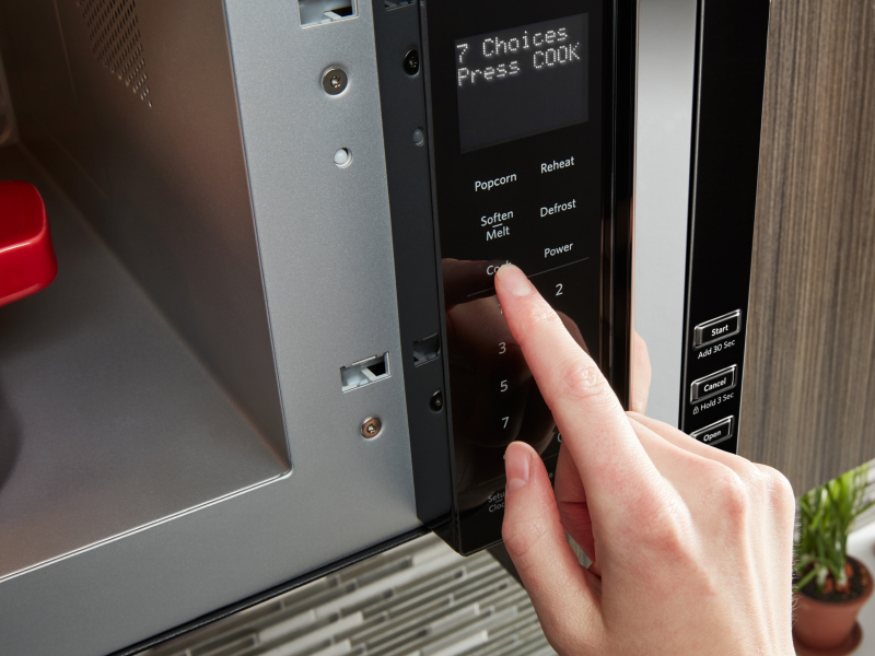 Person selecting a cooking setting on a microwave