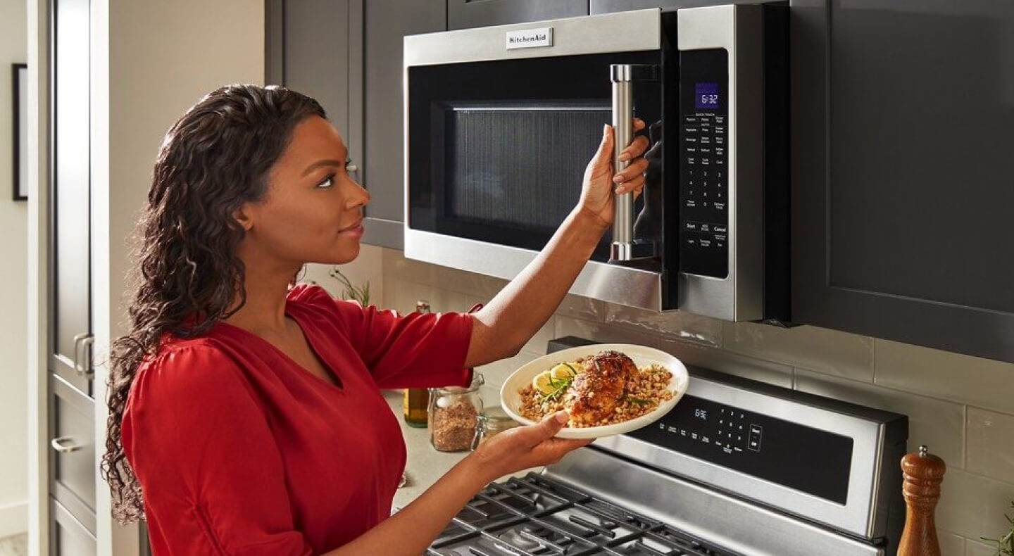 Person using a KitchenAid® microwave to warm food Person using a KitchenAid® microwave to warm food